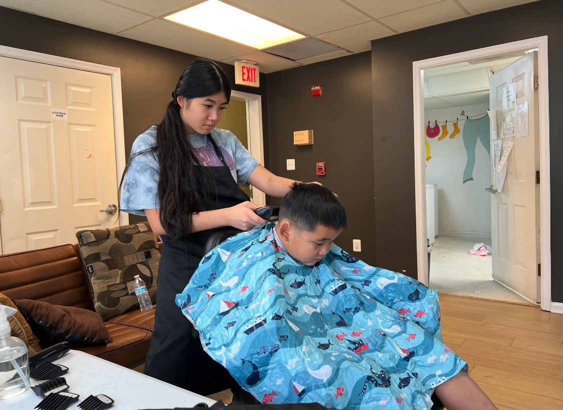 Ava using clippers during a boy's haircut